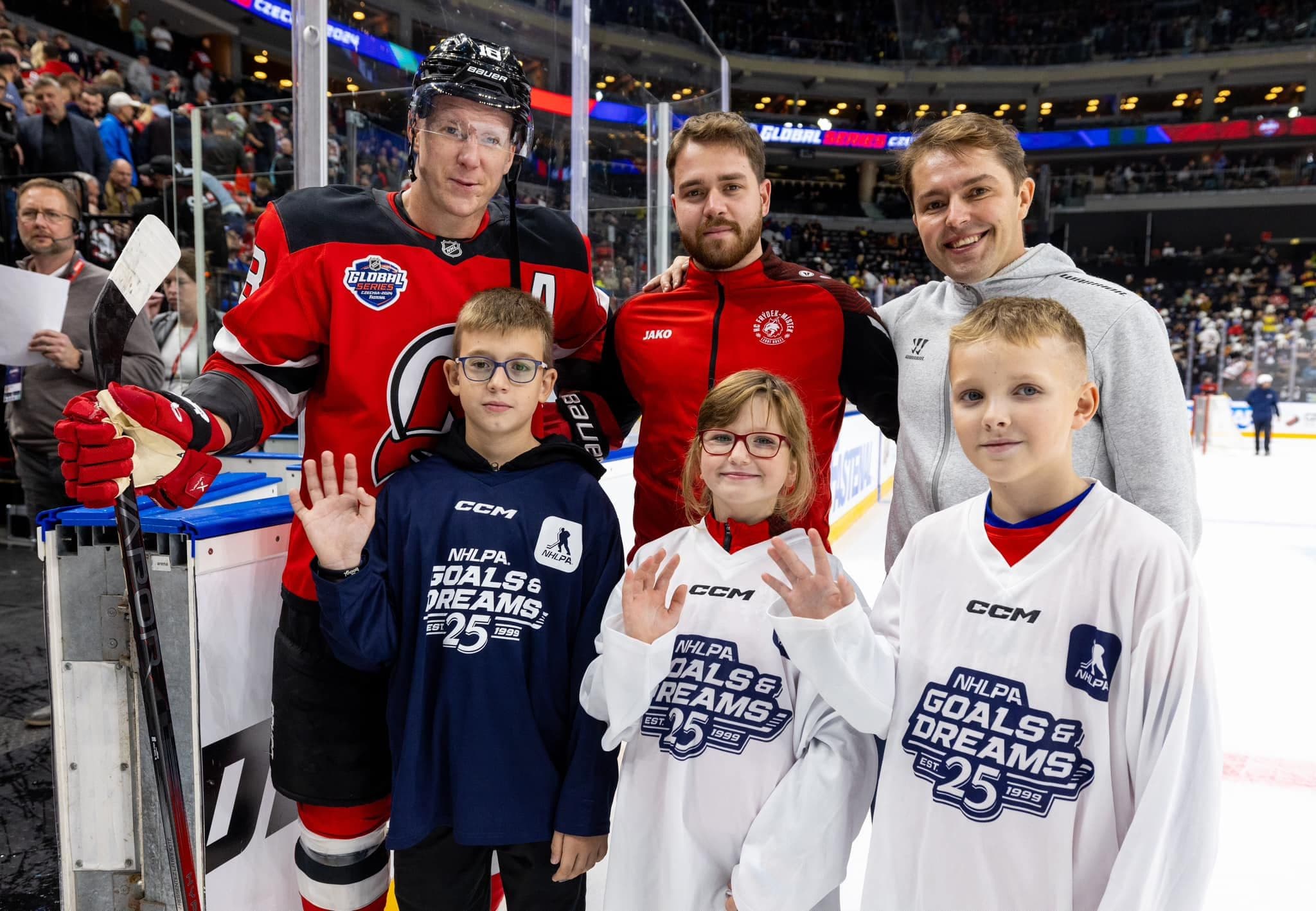 NHL Players standing with young ice hockey players waving